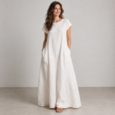 White loose-fit linen maxi dress with short sleeves and side pockets on a model